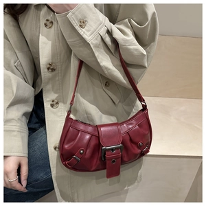 Detail of burgundy ruched shoulder bag showing glossy texture and metal buckle on strap
