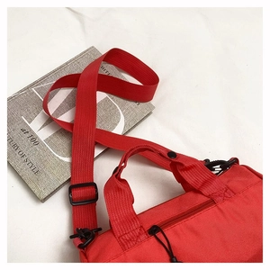 Detail view of the red canvas travel bag featuring adjustable wide shoulder strap and black zipper