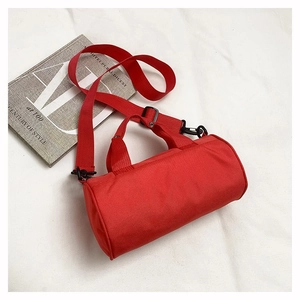Close-up of red cylindrical sports bag with black hardware and adjustable shoulder strap