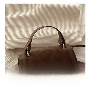 Detail of soft brown suede texture with stylish handle and metallic hardware on the bag