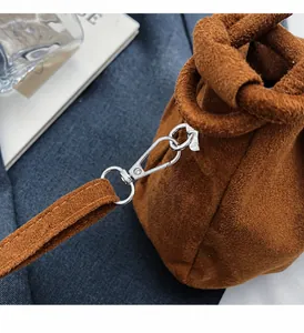 Close-up of premium brown suede bag featuring shiny silver metal hook and handle details