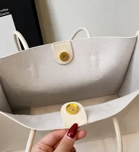 Detail of white textured tote bag showing golden magnetic closure and inner lining