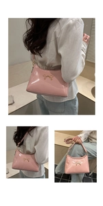 Detail of pink patent leather handbag with gold butterfly accent and long shoulder strap
