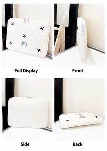 Detail of quilted tablet sleeve with bow prints, zipper closure, and woven fashion label