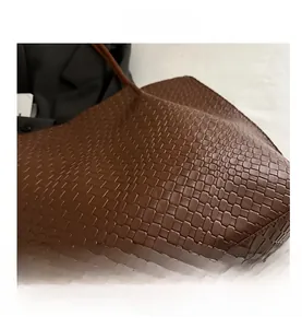 Close-up of the brown woven tote bag showing detailed texture and crossbody strap