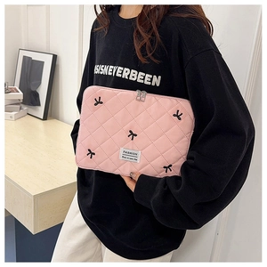 Detail of pink quilted laptop sleeve featuring black bow embroidery and zip closure