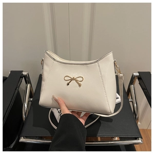 Detail of white PU leather handbag featuring a gold butterfly clasp and fine texture