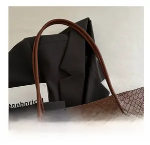 Detailed close-up of comfortable shoulder straps on a brown woven faux leather tote bag