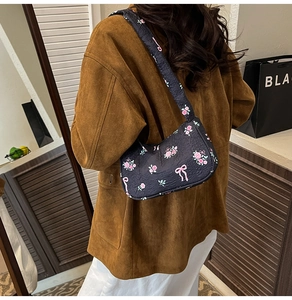 Detail of floral printed shoulder bag with pink roses and bows on black pleated fabric
