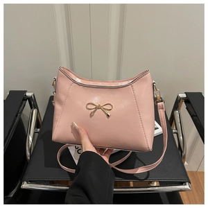Detailed close-up of pink faux leather bag featuring a gold bow metallic ornament