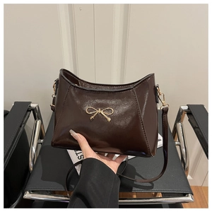 Detailed view of dark brown PU leather handbag featuring a golden butterfly ornament
