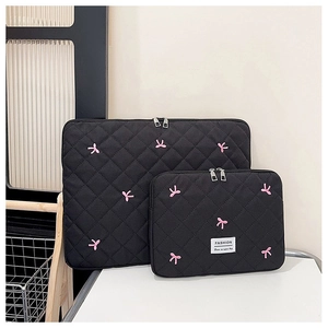 Detail of diamond-quilted laptop sleeve set with pink bow embroidery and metal zipper
