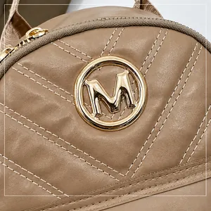 Close-up van beige gewatteerde leren tas met gouden metalen M-logo en ritsdetail