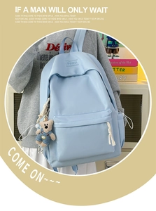 Detail of light blue nylon backpack with cute bear pendant and XINFEIDA logo plate
