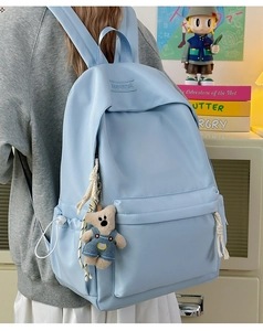 Detail of sky blue nylon backpack with XINFEIDA logo and a cute teddy bear charm