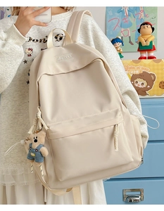 Detail of off-white nylon backpack with cute brown bear plush pendant and zippered pocket