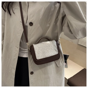 Detail of crossbody bag featuring brown leather and white faux shearling patchwork texture