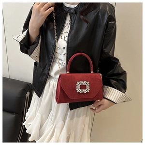 Detail of red suede handbag with square crystal buckle on fashion model outfit