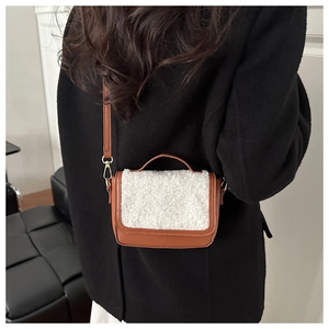 Detail of caramel leather crossbody bag featuring white faux fur trim and gold hardware