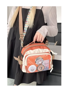Détail du sac JK Ita avec fenêtre transparente montrant des badges anime et accents orange