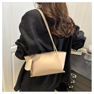 Gros plan d'un sac cabas en cuir beige avec coutures fines et détail de sangle latérale