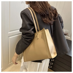 Detalle de piel con grano de litchi y costuras dobles en el bolso tote grande caqui