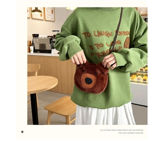 Detail of cute dark brown plush bear head crossbody bag worn over a green sweatshirt