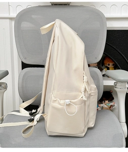 Side view of cream nylon backpack with drawstring pocket and cotton cord zipper detail