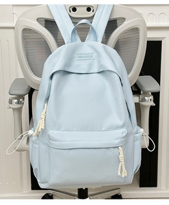 Close-up of light blue nylon backpack with front zipper pocket and embroidered logo