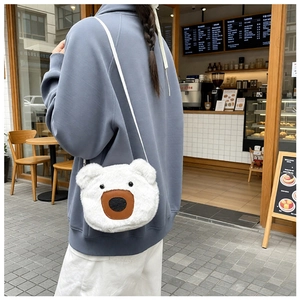 Detail of white plush bear crossbody bag with brown leather snout on a cafe background