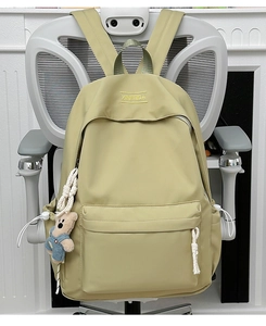 Detail of light green nylon backpack with front zipper pocket and teddy bear pendant