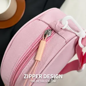 Dettaglio borsa in nylon rosa con cerniera in metallo argento e tirante lungo arancio