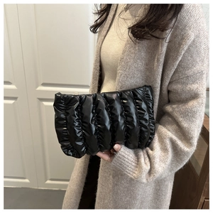 Dettaglio di una pochette nera lucida stile nuvola con texture in pelle a pieghe