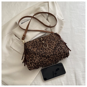 Close-up of leopard print crossbody bag with tassels and gold ring hardware detail