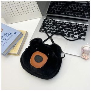 Detail of cute black plush bear crossbody bag on a modern desk with office supplies