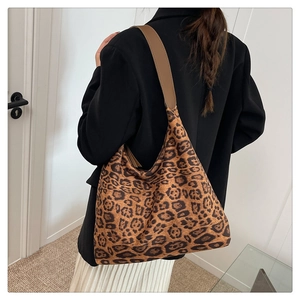 Detail der Leopard-Tragetasche mit braunem Lederriemen getragen über einem schwarzen Blazer
