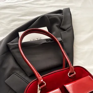 Detail showing red suede texture and burgundy patent leather handle of the shoulder bag