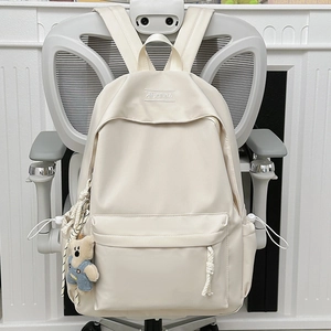 Minimalist beige campus backpack with cute teddy bear charm on ergonomic office chair