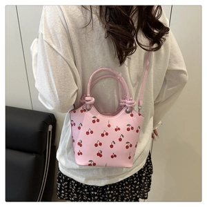 Pink cherry print bucket bag shown on model highlighting size and crossbody strap