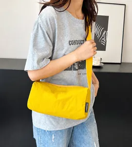 Detail view of bright yellow water-resistant nylon cylinder crossbody bag with shoulder strap