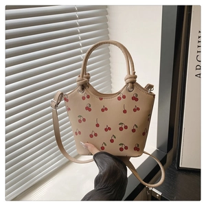 Detail of light beige cherry print tote bag with knot handles and adjustable strap
