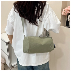 Rear view of a light green nylon crossbody bag with wide strap on a person
