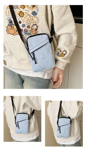 Detail of light blue crossbody phone bag with star patterns and dual zipper compartments