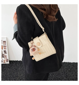 Detail der beige geflochtenen Eimertasche mit Bärenanhänger und Holzmagnetverschluss