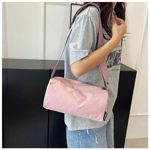 Detail of pink nylon crossbody bag with wide shoulder strap and side brand label logo