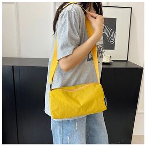 Close-up of lightweight yellow nylon crossbody bag with adjustable strap and zip detail