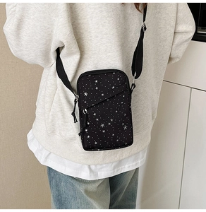 Detail of a casual black canvas crossbody phone bag with star patterns on a male model