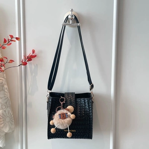 Minimalist black woven bucket bag with teddy bear charm and gold lettering detail