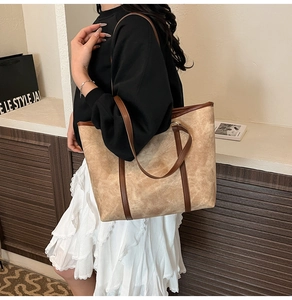 Grande borsa tote kaki con finiture in pelle marrone indossata da una modella in studio