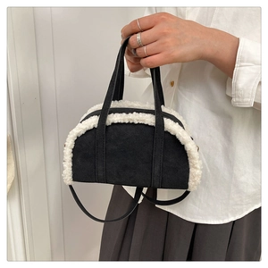 Détail de la garniture en peluche sur un sac bandoulière demi-lune en daim noir